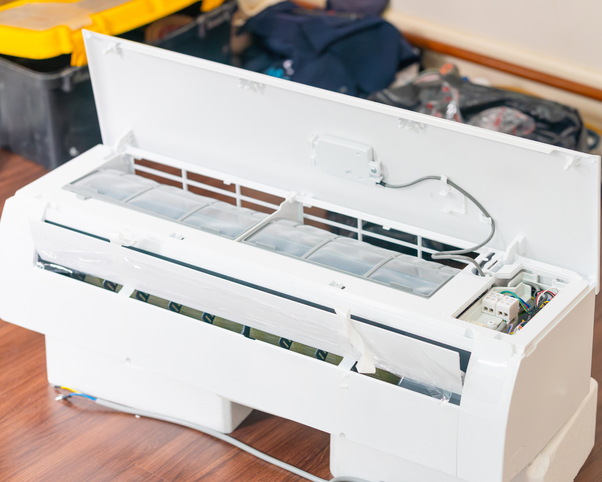 Wall-mounted AC unit with open panel showing filter and internal components, highlighting AC not cooling in a Chester County, PA home due to airflow or maintenance issues