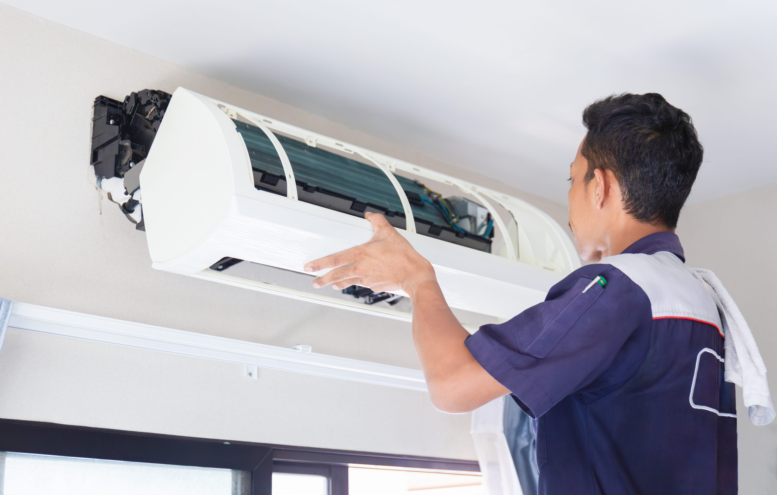 Technician inspecting a wall-mounted AC system during regular maintenance to help Chester County homeowners understand how often to service an air conditioning unit.